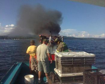 The lobstermen use the hose to keep fuel tank area cool. Osgood towed the vessel away from inner harbor moorings as other moored boats were in the path of the drifting boat. (Photo courtesy Richie Osgood)