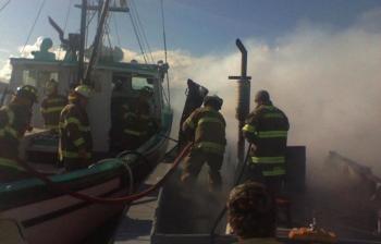 Lincolnville firefighters aboard the “Fundy Spray” douse water on the burning “Big Red.” (Photo courtesy Richie Osgood)