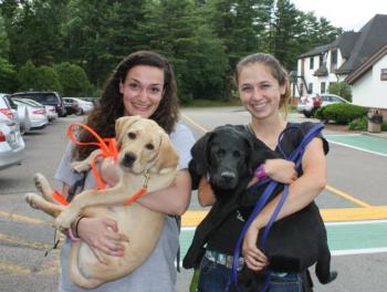 From left and in September, Nikki Viveiros, Unity College Class of 2016 and an adventure Therapy major from Somerset, Mass., and Malcolm, a then-8-month-old Labrador retriever, and Mikala Robinson, Class of 2015 and a conservation law enforcement major from Danvers, Mass., with Malcom’s brother, Mac. (Courtesy Facebook/Guiding Eyes for the Blind at Unity College)