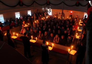With the lights down the singers assemble around the room.