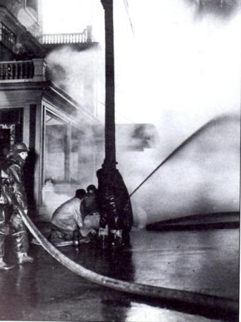 Firefighters stand below the porch of the Rockland Hotel as the Studley Furniture Co. fire spread. (Photo from “Around Rockland: Images of America. Copyright 1996.)