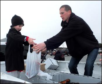 Noah’s daughter Nadia hold a bag as Noah puts lobsters in it.