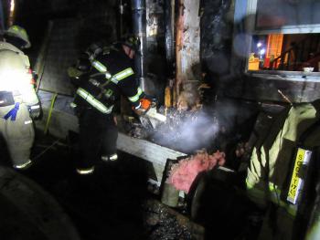 A Rockland firefighter cuts through the wall of the house on Winding Way Saturday night, during work to extinguish a fire there. (Courtesy Rockport Fire Department)