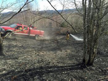 Hope firefighters use portable water tanks to contain and extinguish a woods fire on Sexton Avenue Sunday afternoon. (Courtesy Justin Ford)