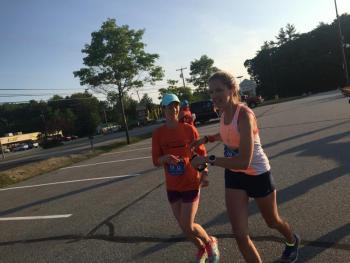 Angela Nasveschuk, left, passes the baton to Runners Orange teammate Kailey Ingerman at the race transition area at Shaw’s supermarket in Wiscasset. SUSAN JOHNS/Wiscasset Newspaper