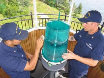 MK3 Joseph Pineda and BMC Sean Dolan clean the 300-mm beacon at Curtis Island to ensure the light's optimum intensity is shining seaward. (Photo by Bob Trapani)