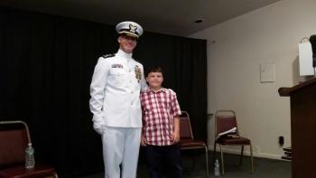 Michael Bollinger, the new commanding officer of the U.S. Coast Guard Cutter, Abbie Burgess, stands on stage with his son Daniel following the Change of Command Ceremony at the Rockland Elks Lodge. (Photo by Sarah Shepherd)