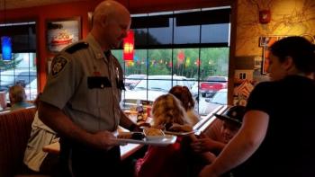 Tim Carroll, Chief Deputy, Knox County Sheriff’s Office, delivers a meal to a table of diners at Applebees. (Photo by Sarah Shepherd)