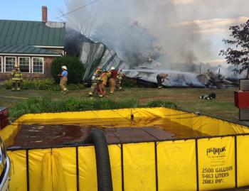 A portable water tank holds water trucked in from offsite, which is then pumped through a fire engine to feed the lines being used by the firefighters. (Photo by Holly S. Edwards)
