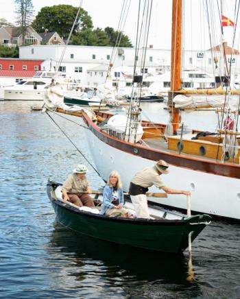 On either end of their dory, Susan and Sam Manning of Camden row Meg Maiden out to the arriving schooners so she can present each with a traditional fresh pineapple welcome. (Photo by Holly S. Edwards)