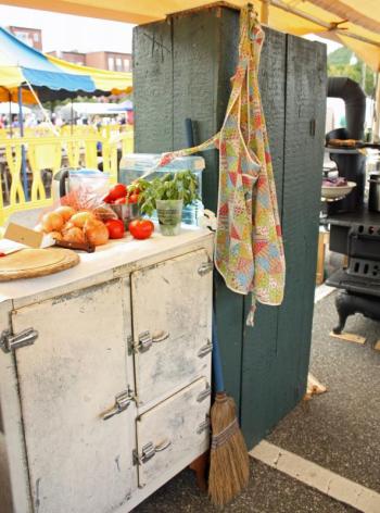 Fresh produce, cabinets, an apron and wood stove, as well as a countertop for rolling pie dough, complete Bridget Qualey’s miniature, portable kitchen on the public landing. (Photo by Holly S. Edwards)