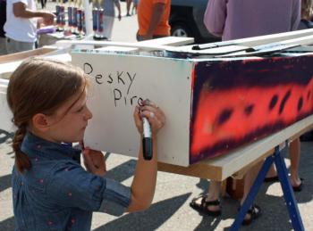 Capt. Brooklyn Rollins adds the name ‘Pesky Pirates’ to the boat she and her brother, Michael, helped make for this year’s Build-a-Boat competition and race. (Photo by Holly S. Edwards)