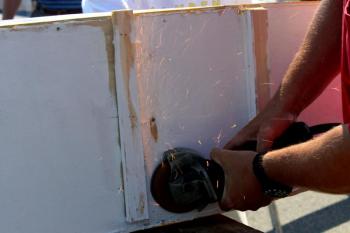 Some last-minute grinding removes the sharp end of a screw from the bottom of one of the boats. (Photo by Holly S. Edwards)