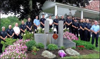 Members of the Rockland Fire and Police departments line up behind the 9/11 Memorial that sits at the corner of the fire station lot. (Photo by Sarah Thompson)