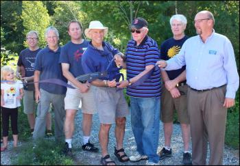 Holding the giant scissors, Camden-Rockport Pathways Committee Chairman Geoff Scott, left, and Camden Select Board member Don White, right, cut the ribbon officially marking completion of the Seabright section of the Camden Riverwalk. (Photos by Chris Wolf)