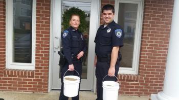 Camden Patrol Officer Brook Hartshorn and Parking Enforcement Officer Mark Bennett hold full buckets of sand ready to be delivered to homes of participants in the Sand for Seniors program. (Photo by Sarah Shepherd)