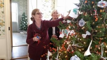 Mary Kay Felton and Susan Freeman, of the Lady Knox Chapter of Daughters of the American Revolution, decorate a holiday tree in the dining room featuring miniature ornaments that are replicas of the china used by General Henry and Lucy Knox. (Photo by Sarah Shepherd)