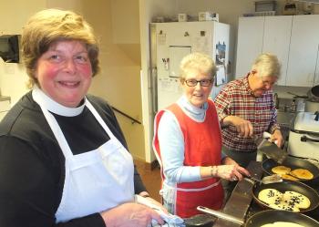 Lael Sorensen, Rector at St. Peters, Nancy Crockett and Steve Alley at the stove preparing pancakes.