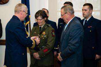 Gov. Paul R. LePage and Rear Adm. Steve Poulin award Specialist Corrie Roberts the Silver Lifesaving Medal at the Maine State House in Augusta on Tuesday, March 28, 2017. Roberts was recognized for her actions during a search and rescue case in October 2015 when she jumped onto a moving lobster boat to assist an unresponsive fisherman. (U.S. Coast Guard photo by Petty Officer 3rd Class Andrew Barresi)