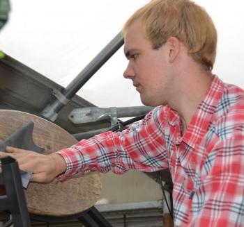 Daniel Reinemann sands the signs in the greenhouse. (Photo by Lynda Clancy)