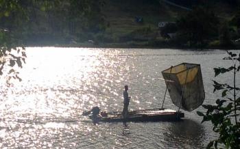 Bill Buchholz, in August 2016, works on cleaning the algae from Hosmer Pond. He obtained an old float from the harbor, and which had been bound for the tinder pile, outfitted it with the scooper, and spent the summer lifting the oxygen-starving algae from the pond. He hauled the green sludge up to his house, and composted it in the woods. (Photo by Lynda Clancy)