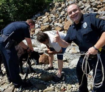 Officer Rick Smith helps the owner secure a calf while Sergeant Daniel Fitzpatrick gives the thumbs up. (photo courtesy of the Belfast Police Department)