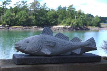 Lindsay’s scultpture “COD,” on permanent display at the Portland Jetport made from St. George granite, about 30” long. (Shown here at Maine Coastal Botanical Gardens).