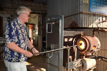 Richard Remsen works with the molten glass as it takes shape in the 2,100-degree oven at the Glass Foundry in West Rockport. (Photo by Lynda Clancy)