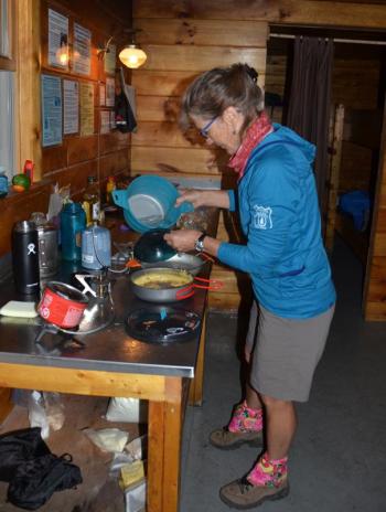 Emily Davis, MaineSport guide, makes dinner in the bunkhouse at Chimney Pond. (Photo by Lynda Clancy)
