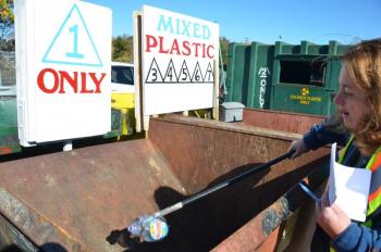 Beth Kwiatkowski mans the front desk at the Midcoast Solid Waste Transfer Station in Rockport, and holds up a No. 1 plastic container. This plastic will get baled and shipped to southern Maine to enter the recycling market. (Photo by Lynda Clancy)