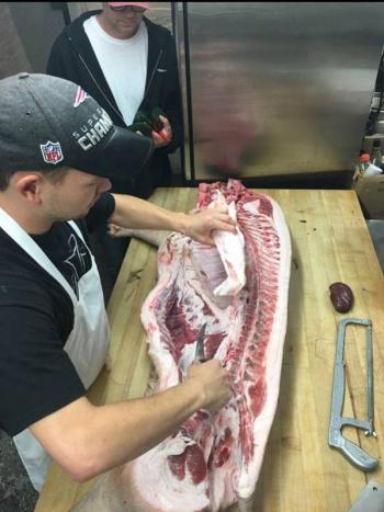 Mallett (upper left) teaching an employee how to break down a pig. (photo courtesy of Elliot Weiner)