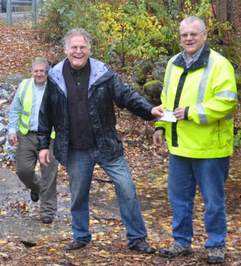 Trout Unlimited’s Dan Daly hands Lincolnville Town Administrator David Kinney the final check for the $208,000 culvert rebuild project. (Photo by Lynda Clancy)