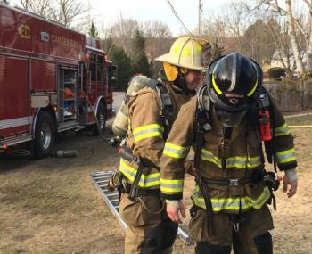 Camden Assistant Fire Chief Andrew Lowe helps a firefighter with SCBA gear.