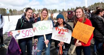 Annika Charland, Lillian Dailey, Ella Tassoni and Anikka Reinwang display their placards during Thursday’s walkout.