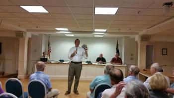Rockport Select Board Chair left the podium to address questions from the audience of non-voting taxpayers July 23. Sitting at the podium, from left, are Rockport Town Manager Rick Bates and Select Board members Jeff Hamilton and Mark Kelley. (Photo by Sarah Shepherd)