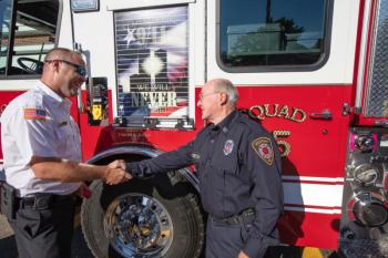 Rockport Fire Chief Jason Peasley and firefighter Charlie Knight exchange a hearty handshake following the dedication of the new “Squad 25” firetruck July 19. (Photo by Peter Ralston)