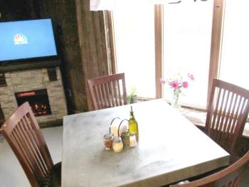 A couple of tables share a cozy nook by a fireplace in the back.