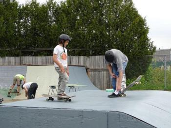 Nine-year-old Finn Cotrell (left foreground) and John Seekins (far right) stand atop one of the ramps in the skatepark. (photo by Erica Thoms)
