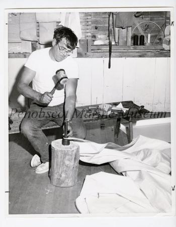 Don Hale of Sargentville, Maine, uses mallet and grommet set to place grommet through sail.
(Photo courtesy Everett "Red" Boutilier)