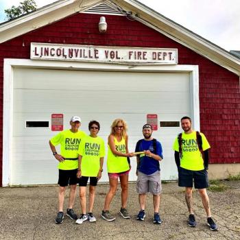 Sam Spinrad, in blue, hands off to Katie Daggett at the Lincolnville Fire Station, as Doug Johnstone, Carol Manley, and James Iandoli look on. (Photo courtesy Run2Respond)
