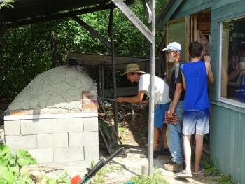 Wessel checks on pizzas cooking in their cob pizza oven. (photo by Erica Thoms)