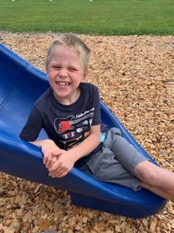 Lincoln Allen is all smiles on the playground slide.