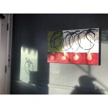 Kim Bernard’s work with the Satori logo reflected beside it. (Photo courtesy of Satori)