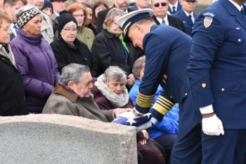 Admiral Karl Schultz, Commandant, U.S. Coast Guard, presents a flag to Patrick Crotty, Lt. Crotty's nephew, during the graveside ceremony. (U.S. Coast Guard Photo by Petty Officer 3rd Class Brian McCrum)