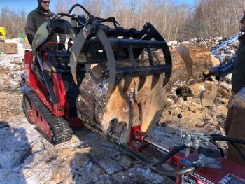 Processing a huge log in the log pile with a small tractor called a Dingo. Photo courtesy Bob MacGregor