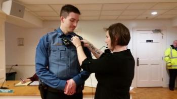 Jonathan Poole’s wife, Ashley, pins his badge on his police uniform during a pinning ceremony at the Rockport Select Board meeting Dec. 9. (Photo by Sarah Shepherd)