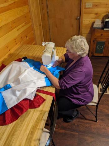 Lynne Dyer, of Belfast, sews together a personal protection equipment gown, using a shower curtain, and special ribbed socks for the wrist cuffs. She is doing this as a volunteer effort to help keep ambulance crews safe as they render aid to sick COVID-19 patients needing transport to hospitals. (Photo courtesy Lynne Dyer)