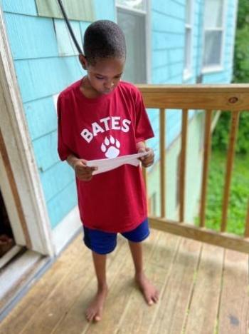 Little Brother Abdikafi Abdikadir reads a hand-delivered letter written by his Big Sister and Bates College mentor, Higera Sevigny. (Photo courtesy Big Brothers Big Sisters of Mid-Maine)