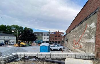 The site of the Year 2020 Camden Time Capsule sits snugly against the wall of a Mechanic Street building. The arrow marks the spot. Don’t forget! (Photo courtesy Alison McKellar)