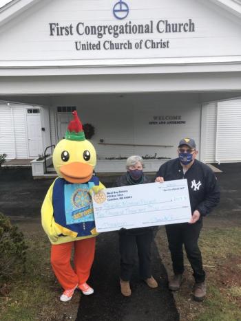 Lucky the Duck and West Bay Rotarian Ray Fink present a check to Shields Mission Project’s administrator Jeanne Denny. (Photo courtesy West Bay Rotary)